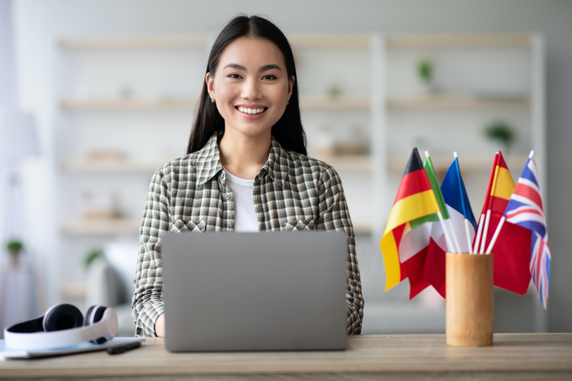 Positive asian woman foreign language teacher using laptop